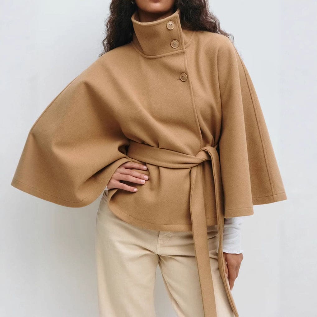 Cape style cropped jacket with high buttoned stand collar, asymmetric button front, wide draped sleeves and a self tie waist belt, worn with wide leg trousers._0