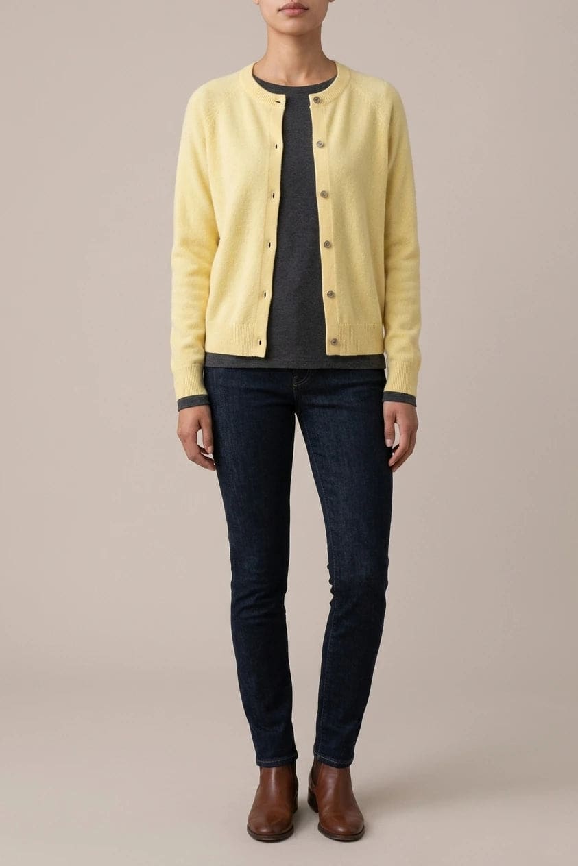 Woman wearing a long sleeve round neck button front cardigan over a grey top with dark slim jeans and ankle boots._0