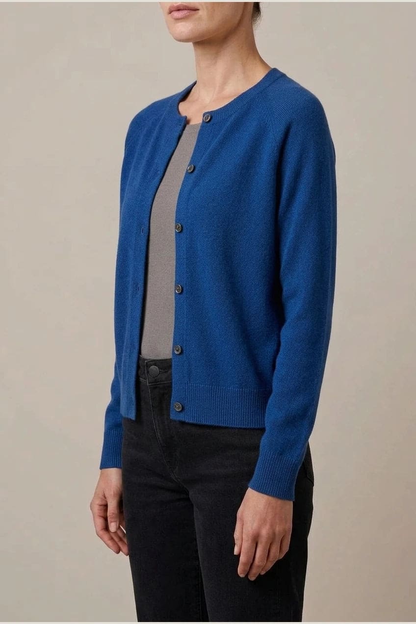 Woman wearing a long sleeve round neck button front cardigan over a grey top with dark slim jeans and ankle boots._10