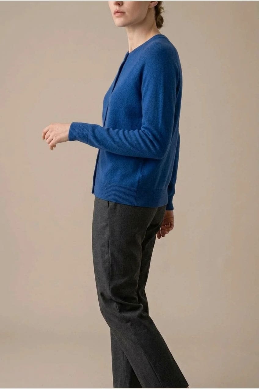 Woman wearing a long sleeve round neck button front cardigan over a grey top with dark slim jeans and ankle boots._11