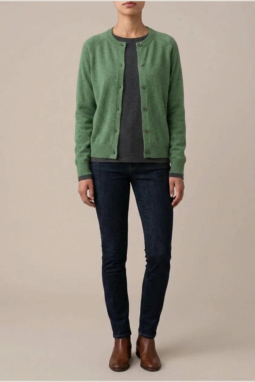 Woman wearing a long sleeve round neck button front cardigan over a grey top with dark slim jeans and ankle boots._13