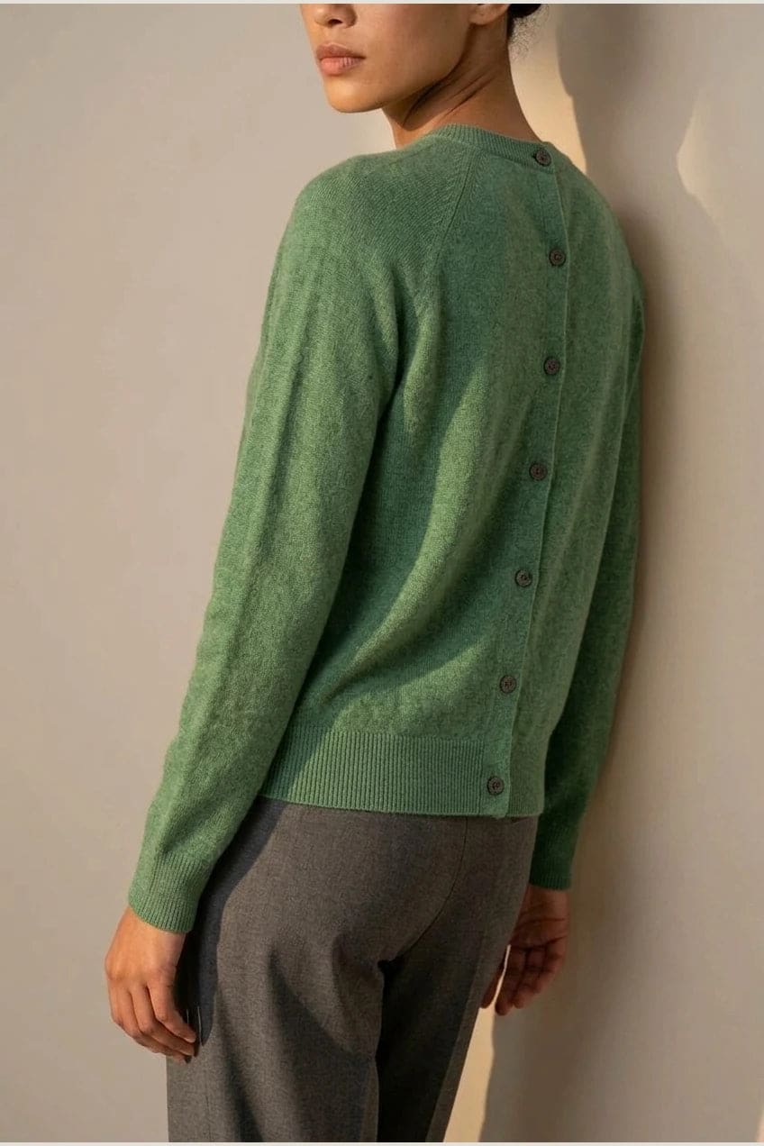 Woman wearing a long sleeve round neck button front cardigan over a grey top with dark slim jeans and ankle boots._15