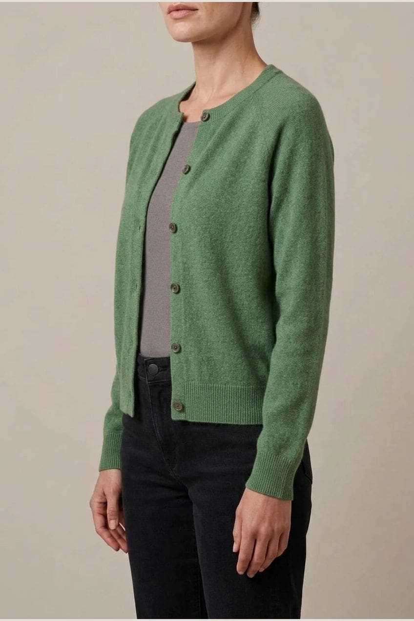 Woman wearing a long sleeve round neck button front cardigan over a grey top with dark slim jeans and ankle boots._16