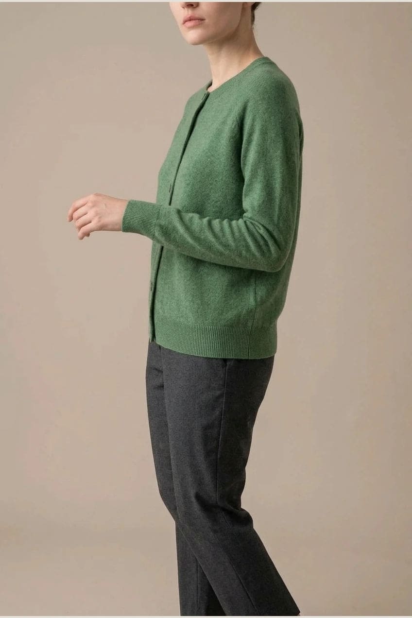 Woman wearing a long sleeve round neck button front cardigan over a grey top with dark slim jeans and ankle boots._17
