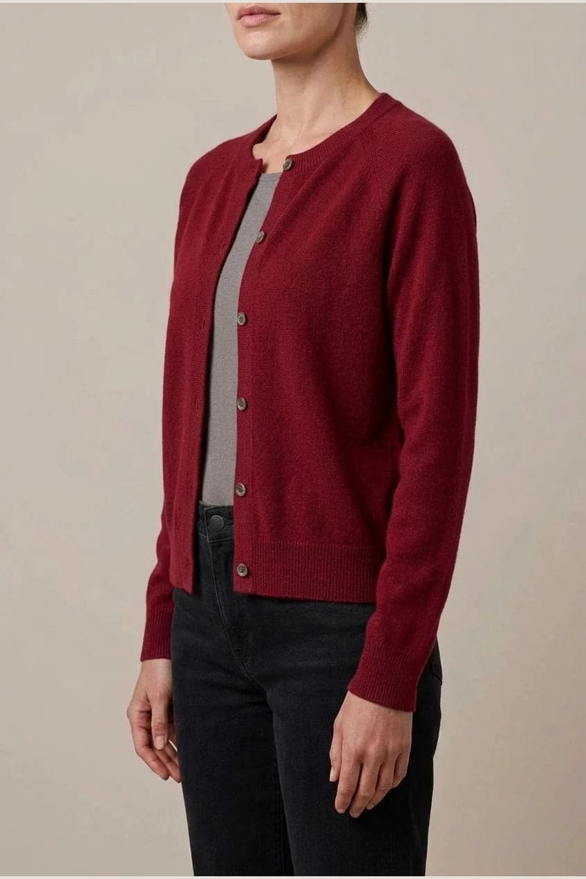 Woman wearing a long sleeve round neck button front cardigan over a grey top with dark slim jeans and ankle boots._22