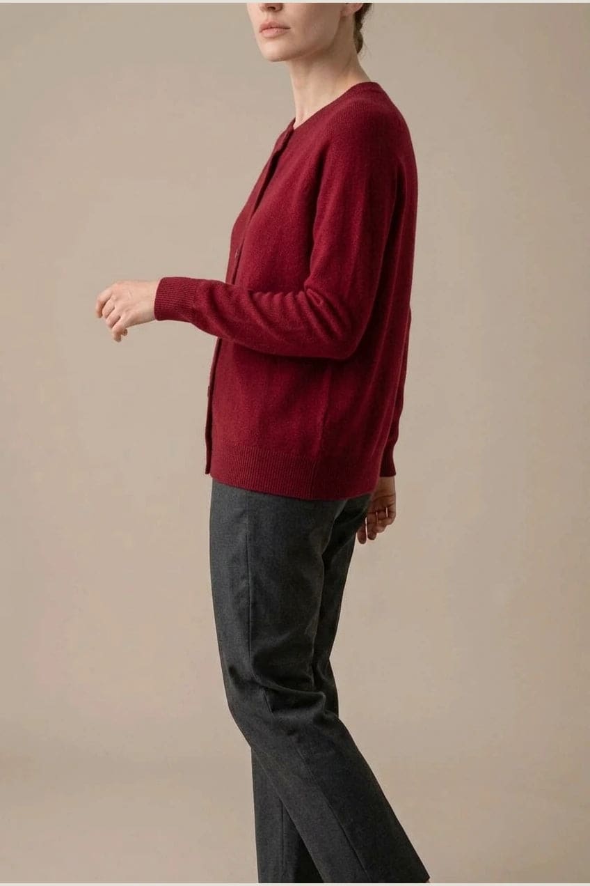 Woman wearing a long sleeve round neck button front cardigan over a grey top with dark slim jeans and ankle boots._23