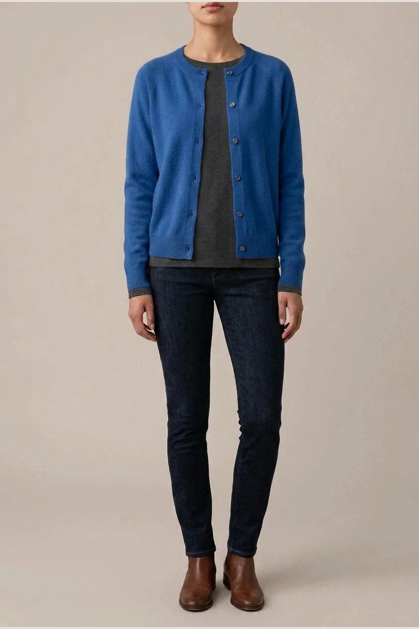 Woman wearing a long sleeve round neck button front cardigan over a grey top with dark slim jeans and ankle boots._7