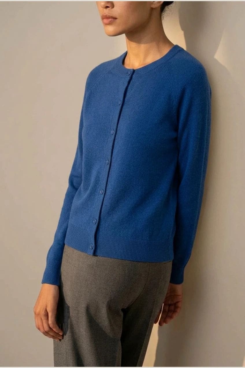 Woman wearing a long sleeve round neck button front cardigan over a grey top with dark slim jeans and ankle boots._9