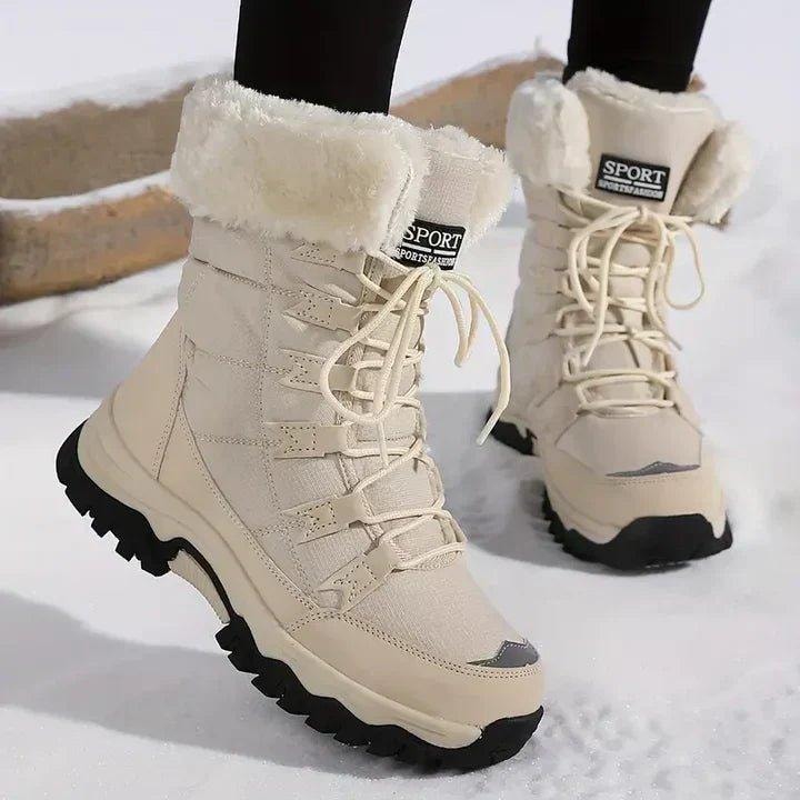Pair of cream ankle-length winter boots with plush white faux fur cuffs, cream laces, reinforced toe accents, and black lug soles shown on snow.