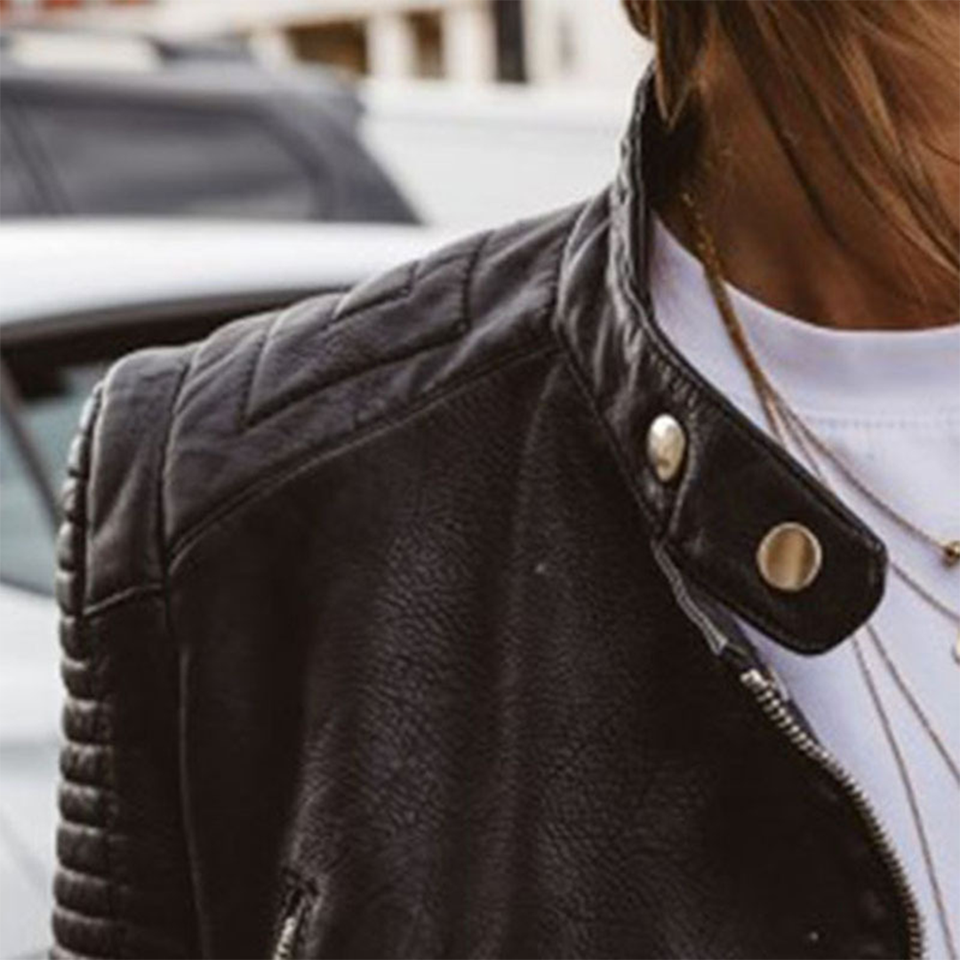 Detail of the jacket’s quilted shoulder and upper sleeve beside the snap-tab collar and angled zip front.