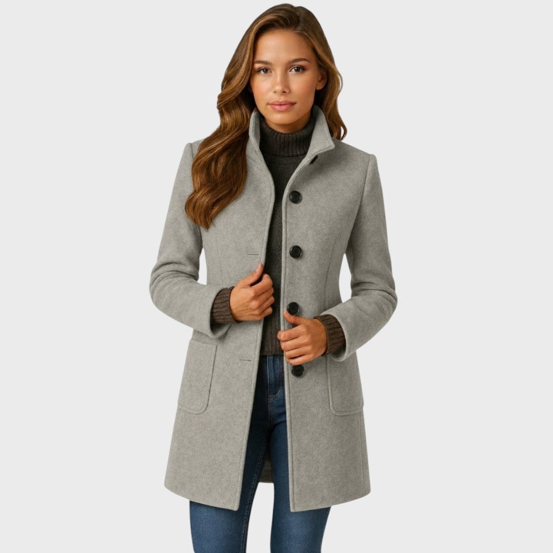 Front view of the fitted mid-length coat in light gray with a structured stand collar, dark buttons, and two front patch pockets.