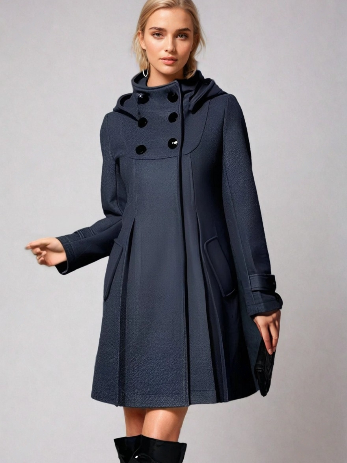 Three-quarter view of the dark navy hooded coat showing its flared shape, high neckline, front pockets, and buttoned cuffs.