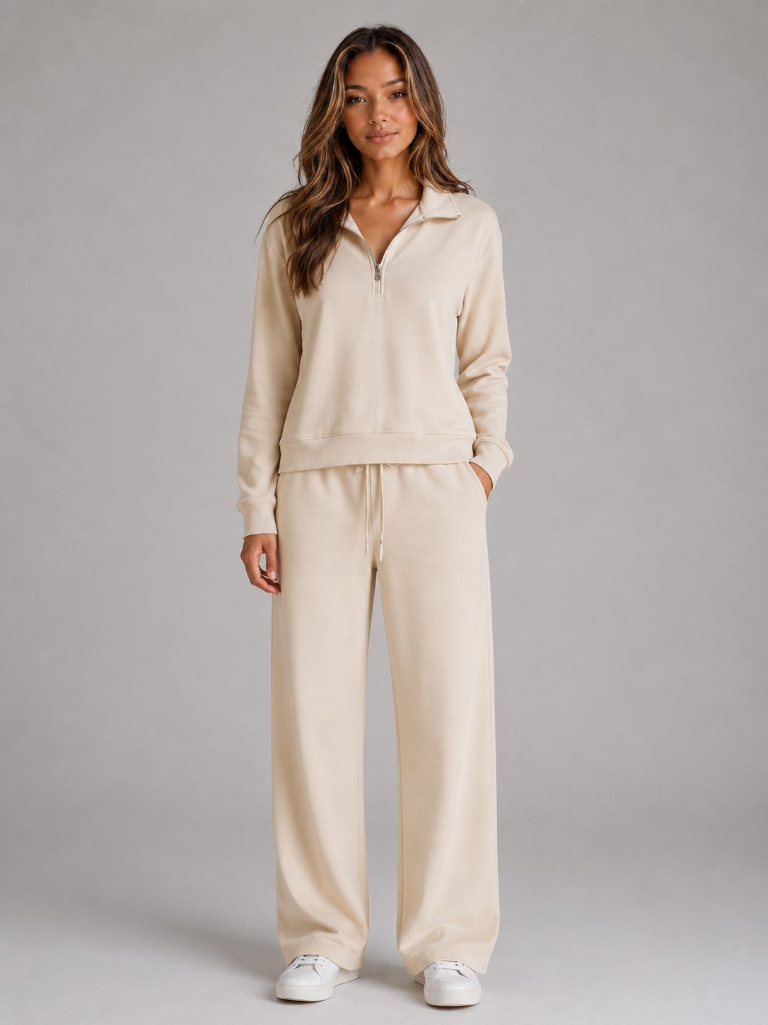 Front view of a beige two-piece lounge set with a collared half-zip sweatshirt, wide-leg trousers, and white sneakers.