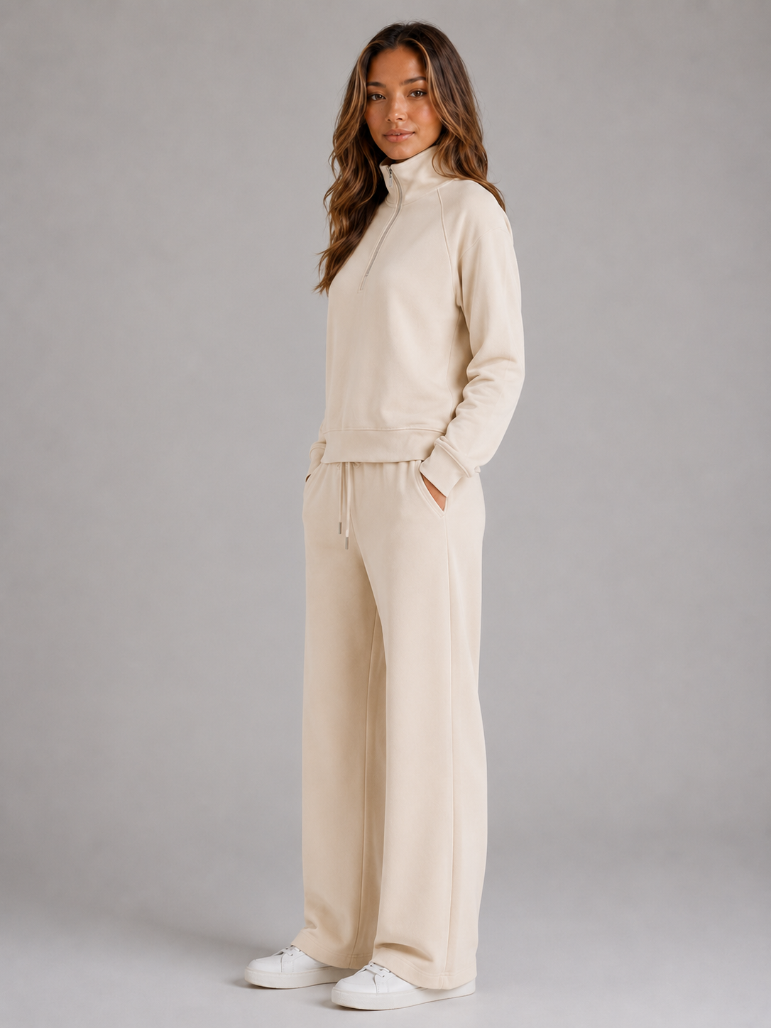 Three-quarter view of the beige lounge set, highlighting the half-zip collar, side pockets, and trouser drawstring.