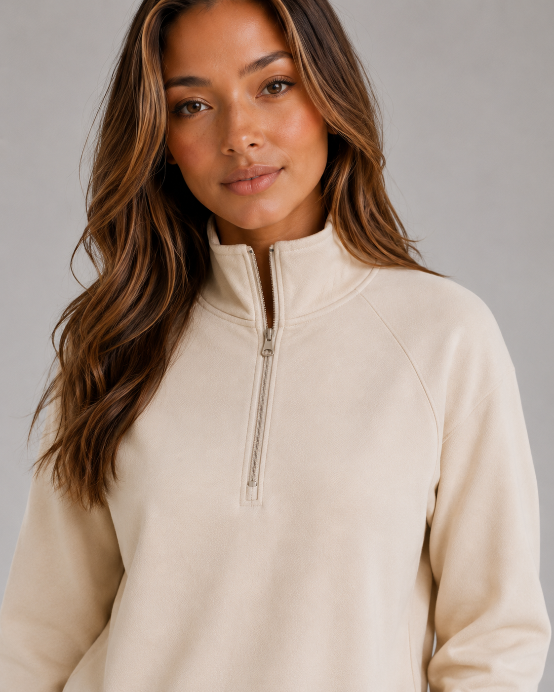 Close-up of the beige sweatshirt showing its raised collar and partially zipped neckline.