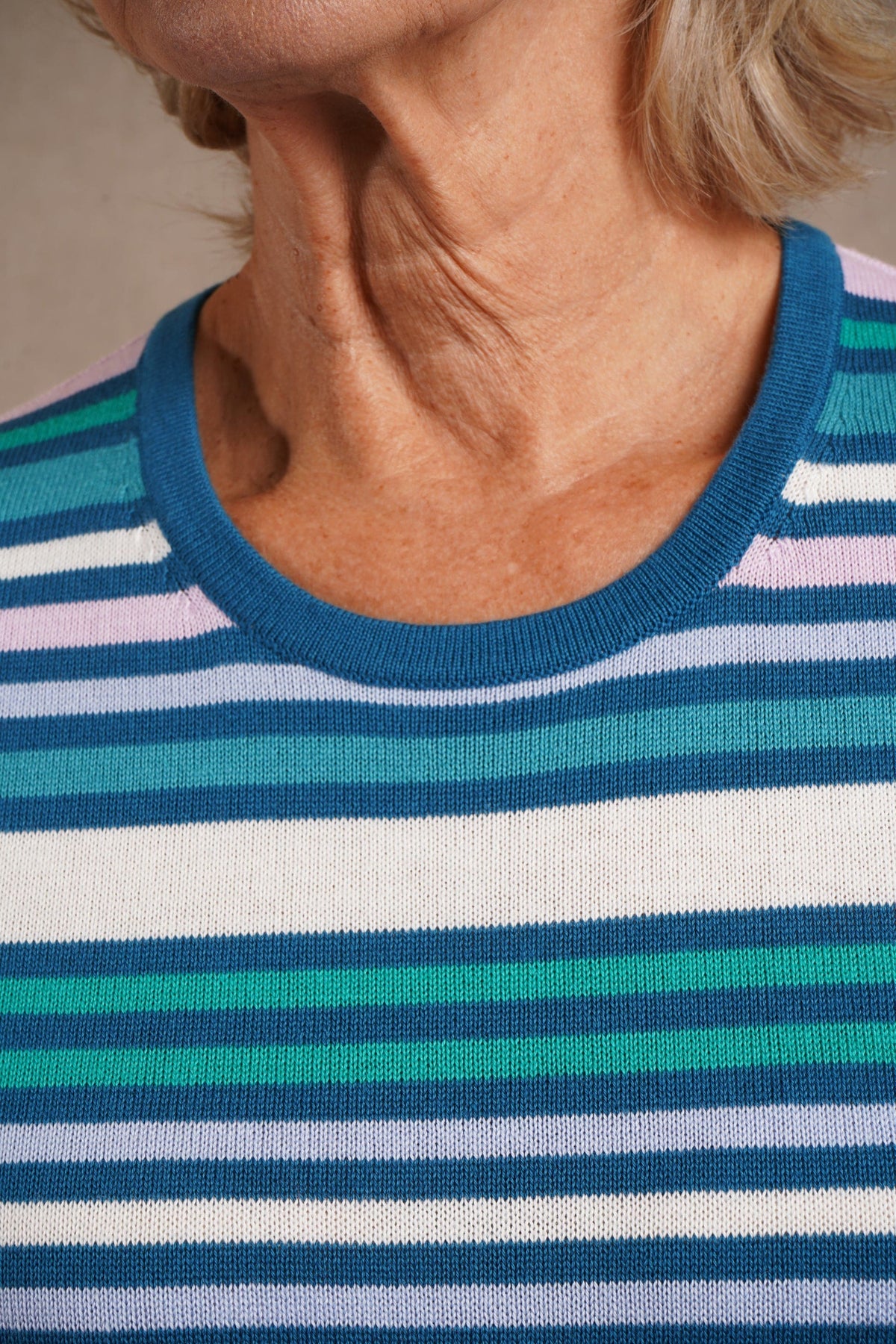 Woman wearing a multi striped three quarter sleeve crew neck knitted jumper with ribbed neckline, cuffs and hem, with dark trousers._10