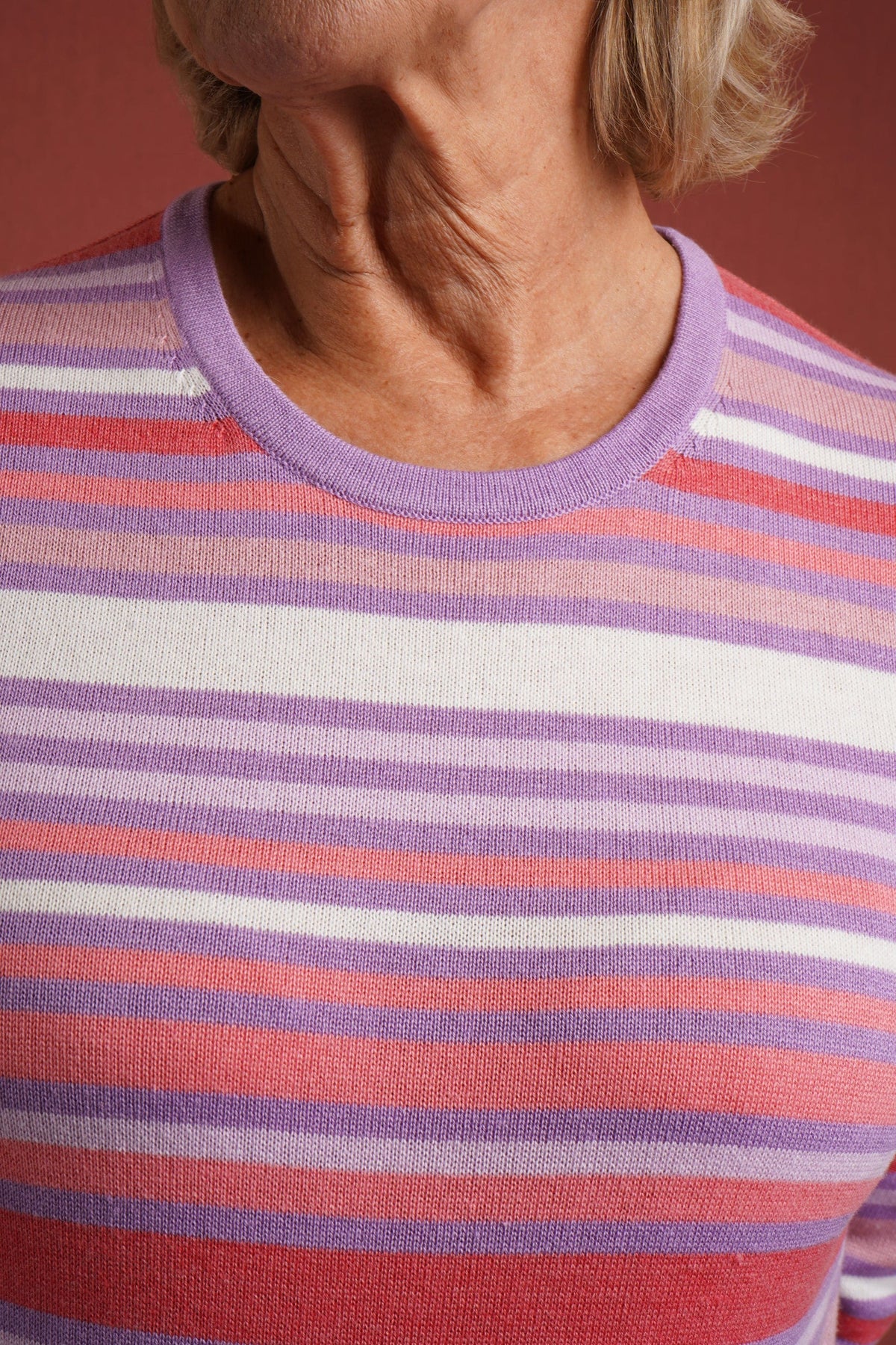 Woman wearing a multi striped three quarter sleeve crew neck knitted jumper with ribbed neckline, cuffs and hem, with dark trousers._5