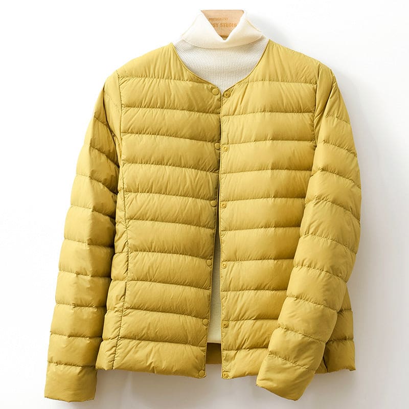 A collarless quilted puffer jacket with a snap button front is shown hanging against a light background._0