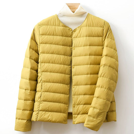A collarless quilted puffer jacket with a snap button front is shown hanging against a light background._0