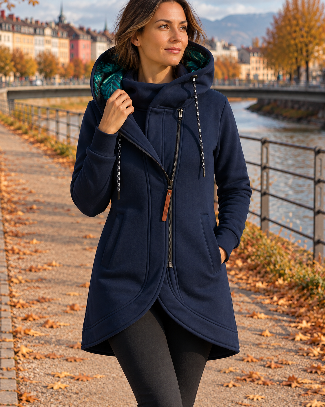 Navy blue asymmetric zip jacket with an oversized drawstring hood and curved hem, worn for a casual outdoor look.