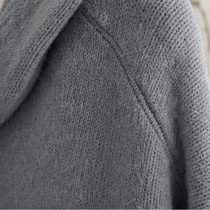Close-up of the gray cardigan's hood edge, shoulder seam, and textured knit.