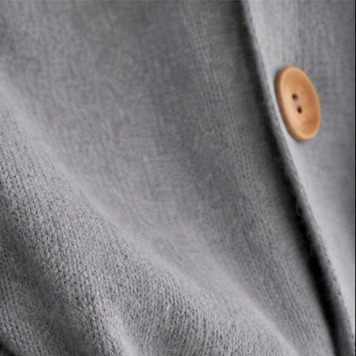 Detailed view of the gray cardigan front edge and a wooden button.