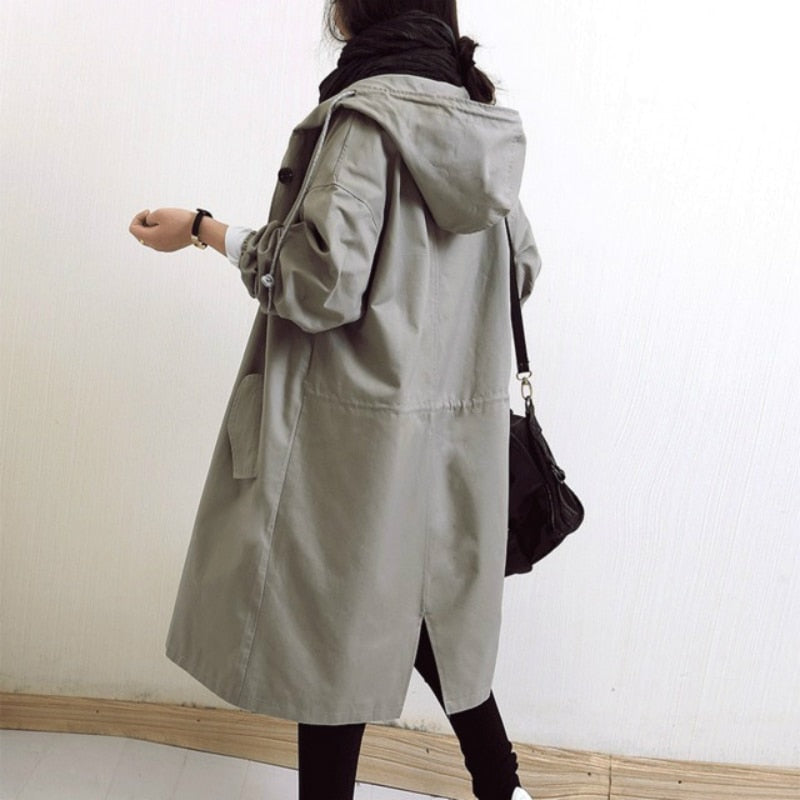 Rear view of a light gray hooded trench coat with a longer split hem, gathered waist drawstring, and loose sleeves.