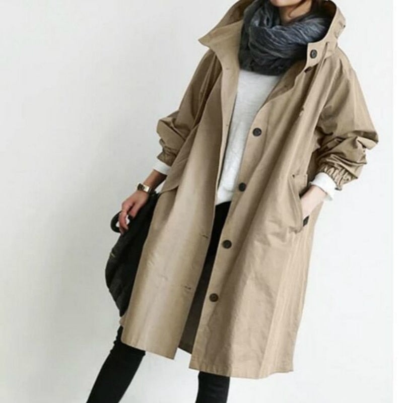 Front view of a beige hooded trench coat with button closure, adjustable sleeve cuffs, drawstring waist, and large front pockets.