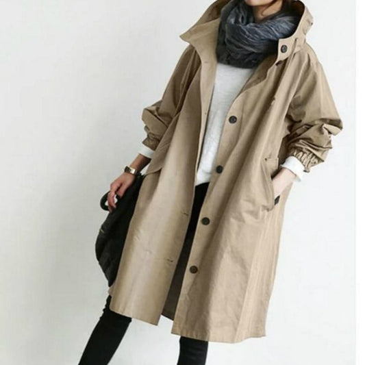 Beige hooded longline coat worn open over a light top, with rolled sleeves, front buttons, and roomy side pockets.