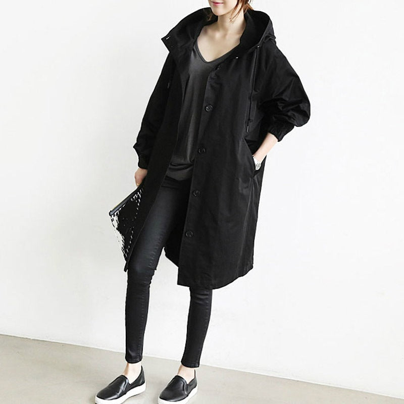 Black hooded longline coat styled with black jeans and slip-on shoes, showing its relaxed fit and button front.