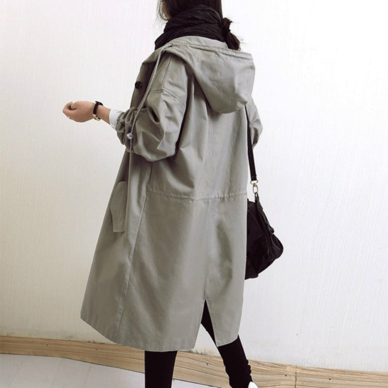 Light gray hooded longline coat viewed from the back, with a drawstring hood, gathered waist seam, and split back hem.