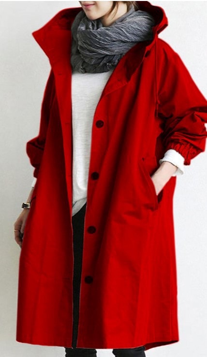 Bright red hooded longline coat worn open with a scarf, displaying its front buttons, raised collar, gathered sleeves, and roomy pockets.