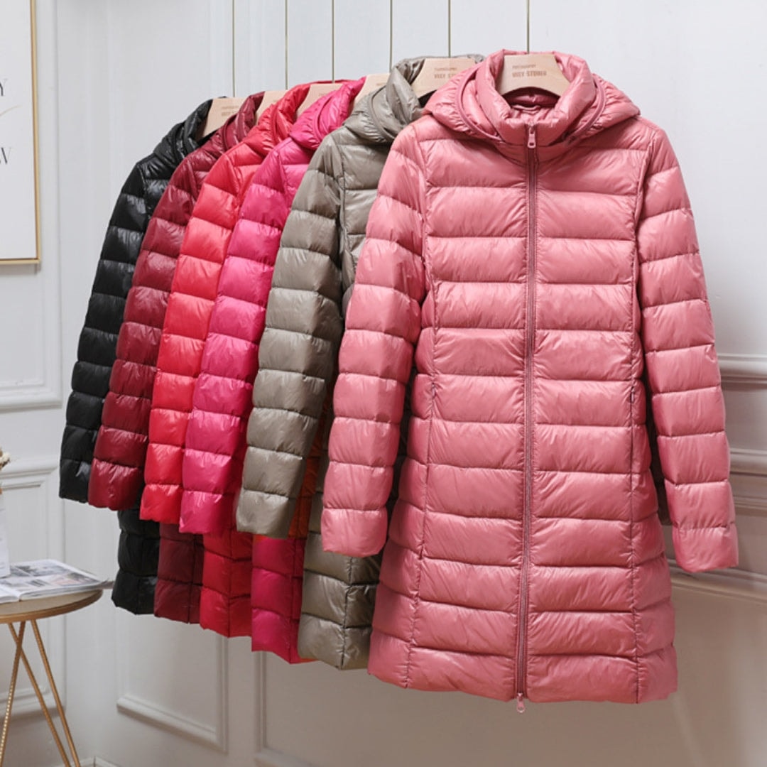 Pink hooded longline puffer jacket displayed at the front of a row of jackets in black, red, fuchsia, and taupe.