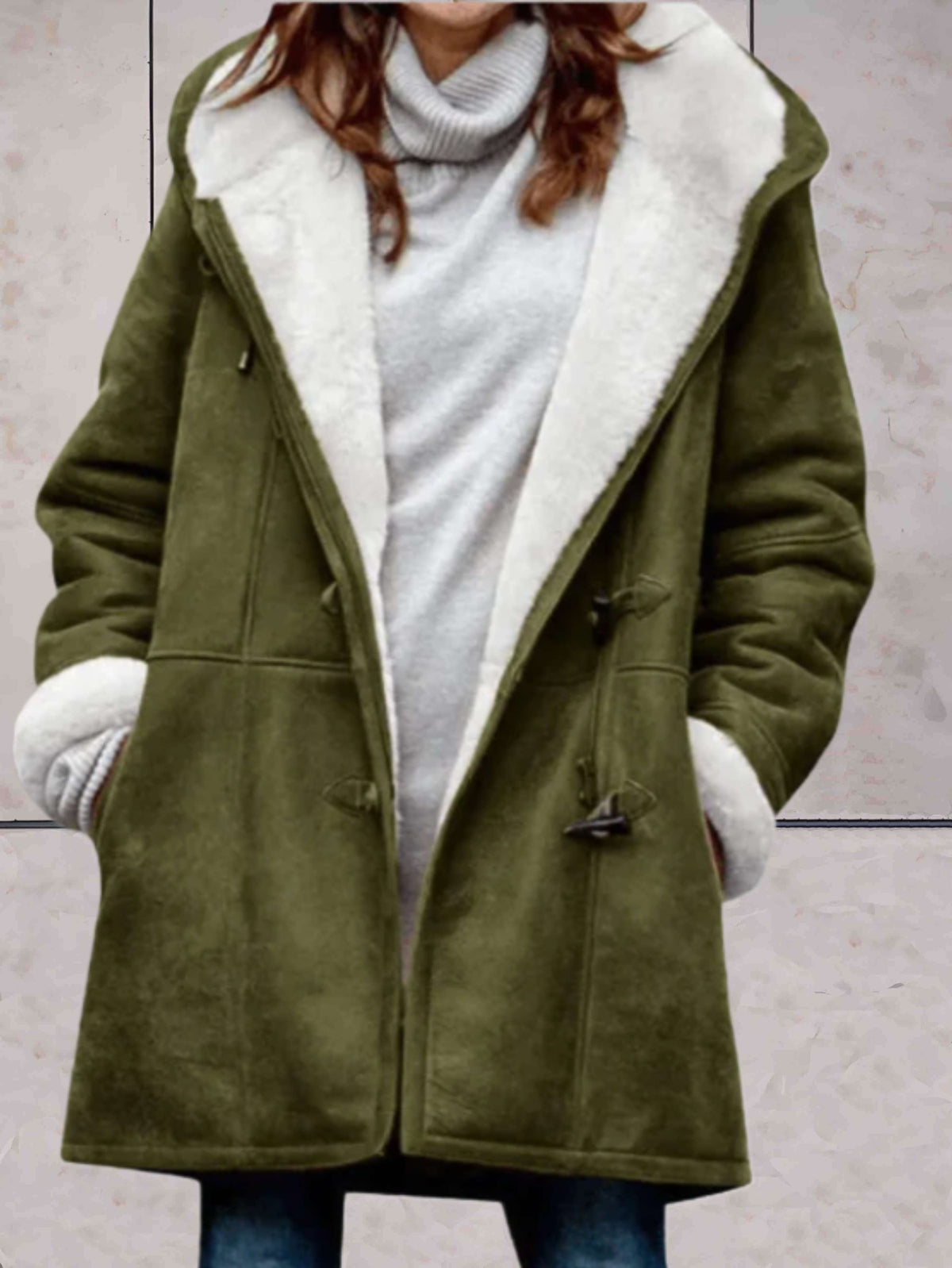 Woman wearing an open hooded coat with contrast borg lining, toggle fastenings and front pockets, over a roll neck knit and jeans._0