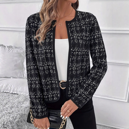 Black jacket with a contrast check pattern, open front, rounded collarless neckline, and long sleeves, styled over a white top and black trousers.