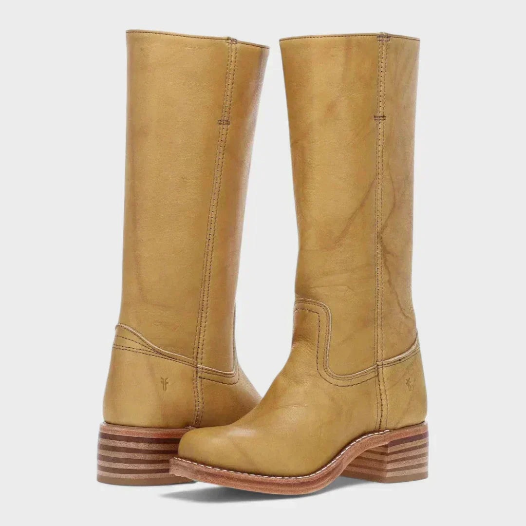 Mustard tan knee-high boots with tall straight shafts, stitched ankle panels, rounded toes, and layered block heels.