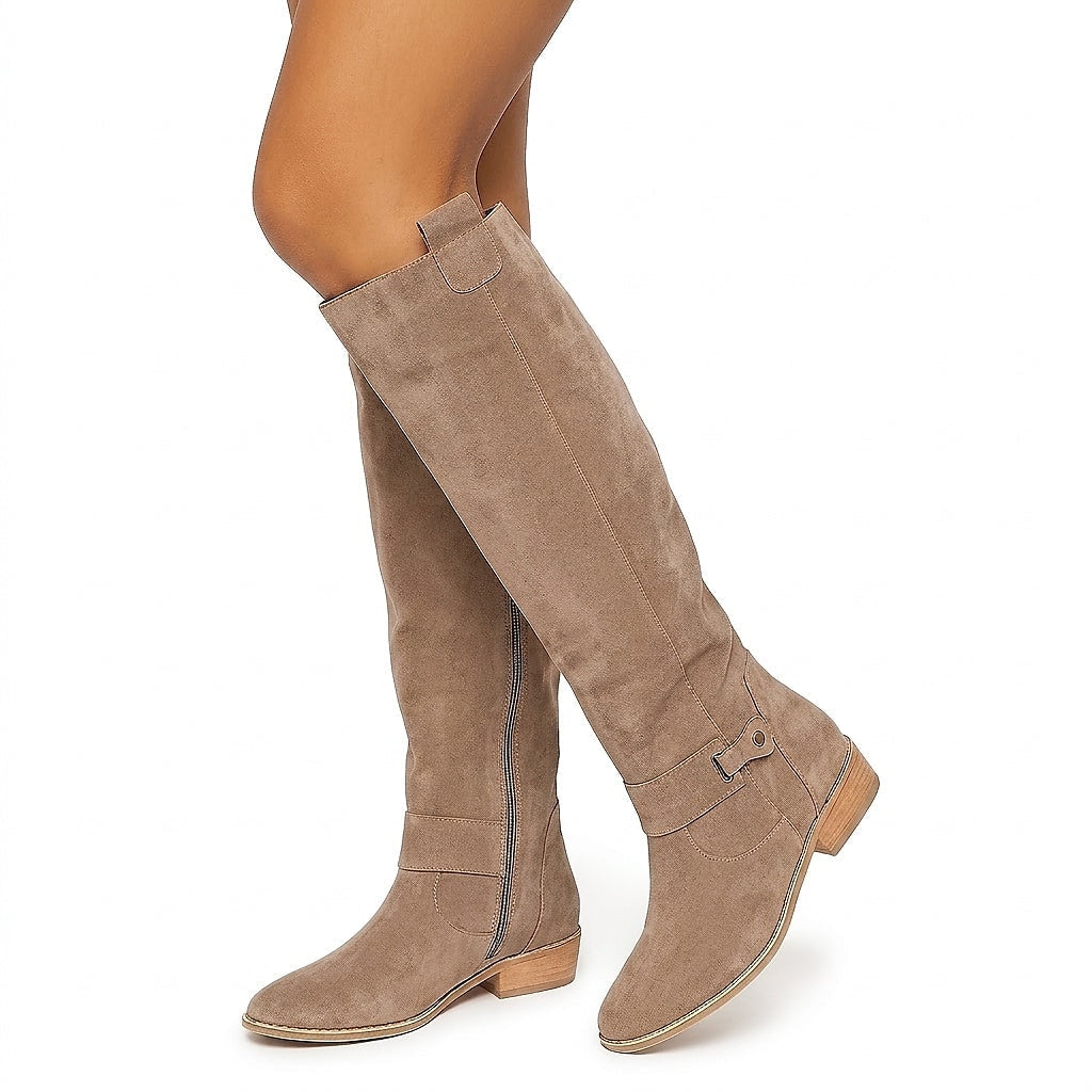Taupe knee-high boots shown crossed, highlighting the rounded toes, side zippers, decorative ankle straps, and low block heels.