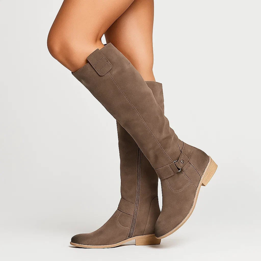 Brown knee-high boots displayed from the side with a full-length outer zipper, ankle strap detail, and practical block heels.