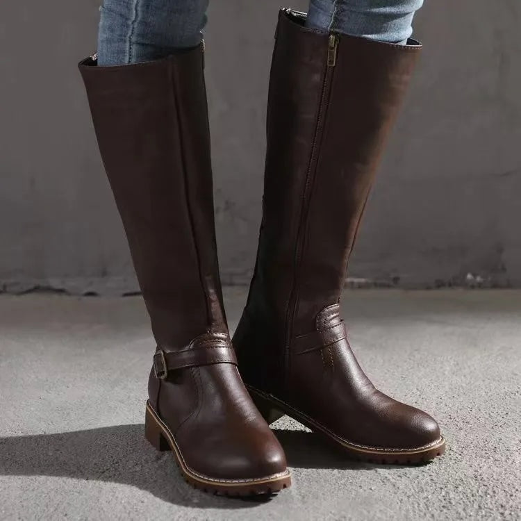 Dark brown knee-high boots paired with jeans, shown from the front with side zippers, ankle buckles, and low heels.