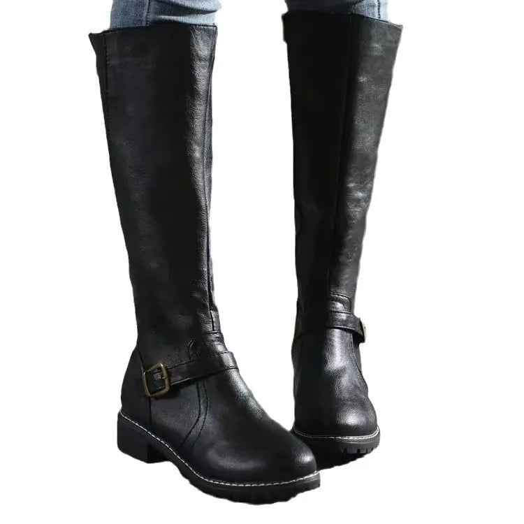 Black knee-high boots displayed against a light background, clearly showing the rounded toes, ankle buckle detail, and chunky tread.