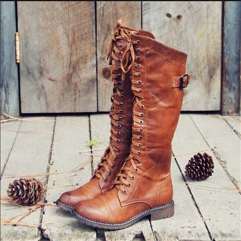 Brown knee-high lace-up riding boots with rounded toes, low block heels, and side buckle straps, shown in a three-quarter view.