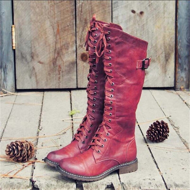 Red knee-high riding boots featuring full-length front lacing, rounded toes, low block heels, and adjustable side buckle straps.