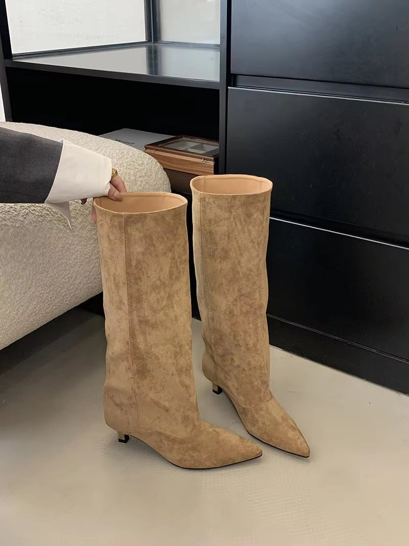 Pair of tan knee-high boots standing together, highlighting their pointed toes, slim heels, and tall shafts.