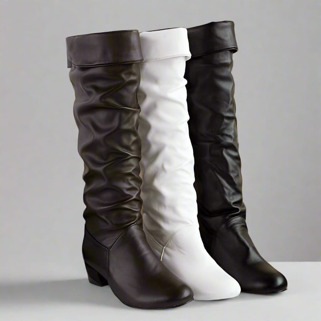 Woman wearing knee high slouchy boots with round toe paired with distressed jeans on a sandy outdoor surface._3