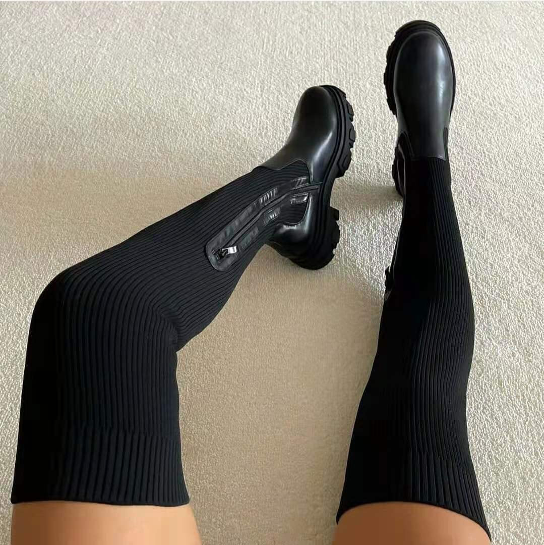 Black knee-high boots shown from above, highlighting their ribbed shafts, side zippers, and chunky treaded soles.