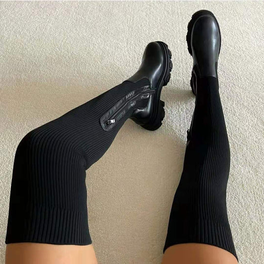 Black knee-high boots shown from above, highlighting their ribbed shafts, side zippers, and chunky treaded soles.