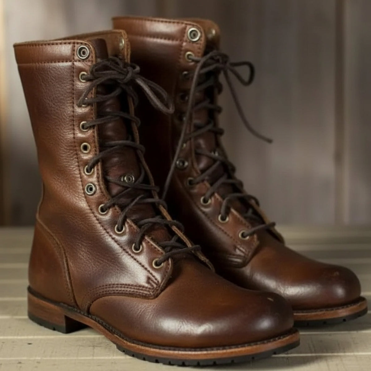 Brown pair of lace-up ankle boots displayed upright, showing the round toes, metal eyelets, tied laces, and textured soles.