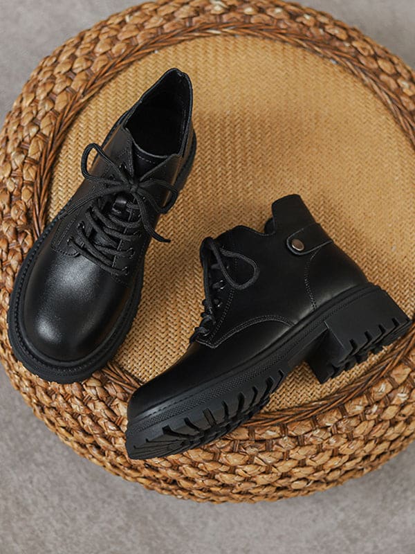 Person lacing up black combat boots with round toe and platform sole while wearing a black skirt._11