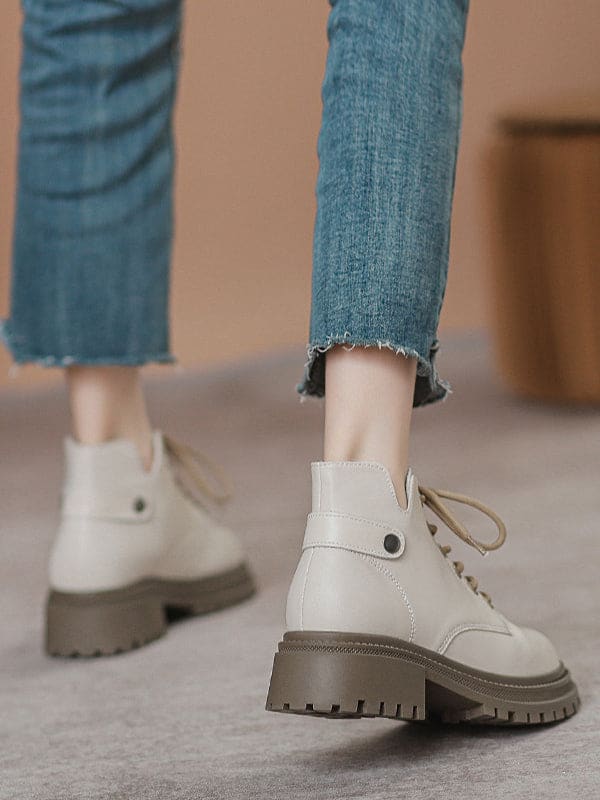 Person lacing up black combat boots with round toe and platform sole while wearing a black skirt._2