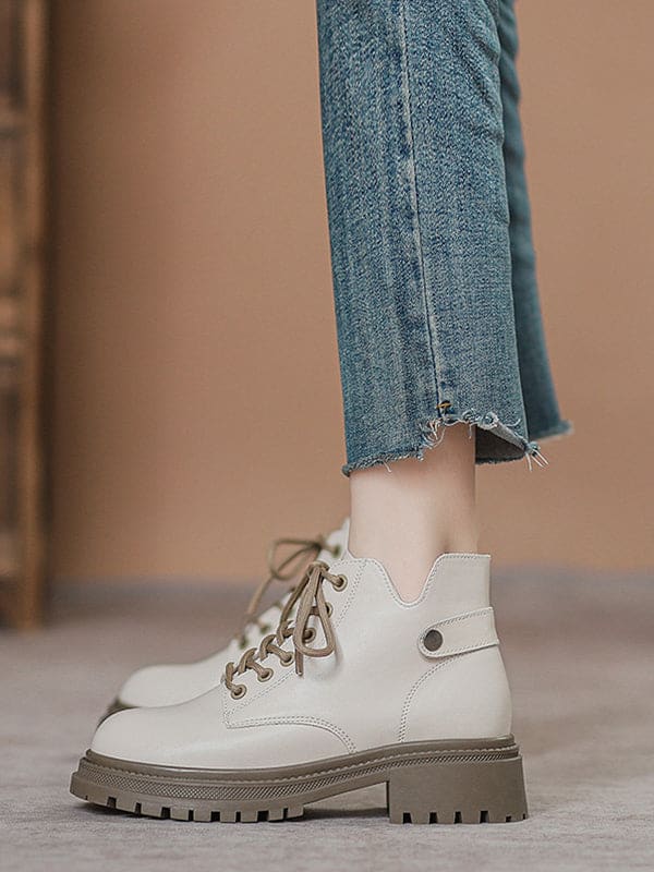 Person lacing up black combat boots with round toe and platform sole while wearing a black skirt._3